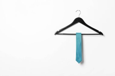 Beyaz duvarında açık mavi kravat olan bir askı. Metin için boşluk
