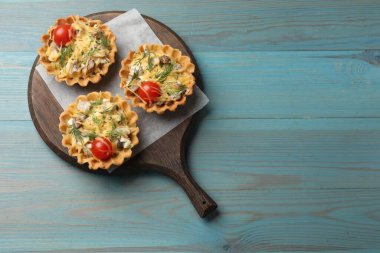 Peynirli, domatesli, mantarlı ve turkuaz ahşap masadaki dereotlu turtalar. Metin için boşluk