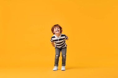 Sarı arka planda dans eden küçük mutlu çocuk