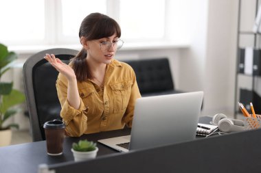 Woman using video chat during webinar at table in office