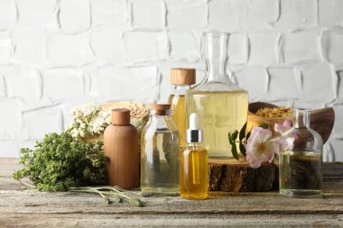 Aromaterapi. Tahta masadaki farklı temel yağlar, bitkiler ve çiçekler.