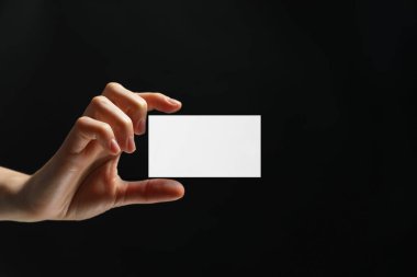 Siyah arka planda boş kartviziti olan bir kadın, yakın plan. Tasarım için model