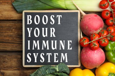 Bağışıklık sistemini uygun bir diyetle güçlendir. Farklı yiyecekler ve tahta üzerinde küçük karatahta düz yatıyordu.