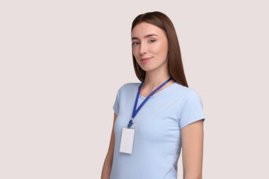 Woman with blank badge on grey background, space for text