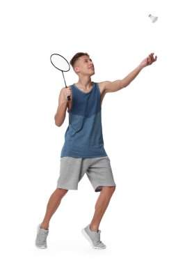 Beyaz arka planda raketle badminton oynayan genç adam.