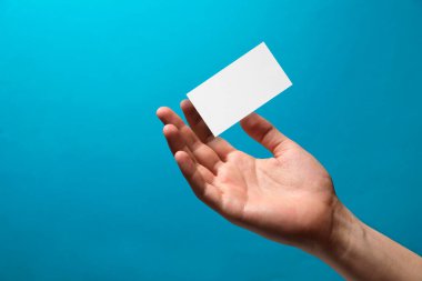 Açık mavi arka planda boş kartviziti olan adam, yakın plan. Tasarım için model