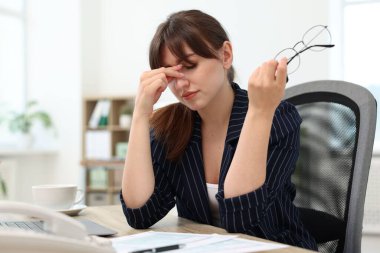 Ofiste acı çeken gözlüklü bir kadın.
