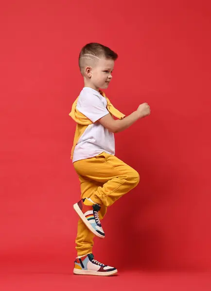 stock image Happy little boy dancing on red background