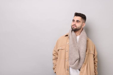 Açık gri arka planda, sıcak eşarplı yakışıklı bir adam. Metin için boşluk