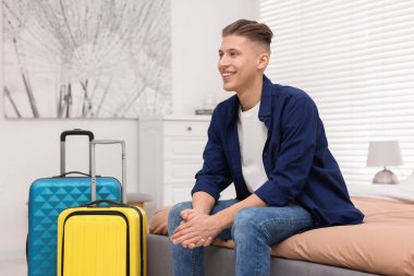 Gülümseyen misafir şık bir otel odasında yatakta dinleniyor.