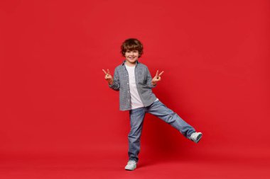 Kırmızı arka planda dans eden mutlu küçük çocuk. Metin için boşluk