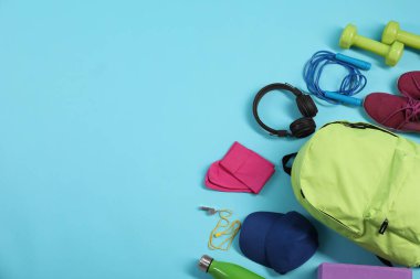 Açık mavi arka planda, düz zeminde farklı spor aletleri. Metin için boşluk