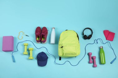 Açık mavi arka planda farklı spor ekipmanları, düz yatış