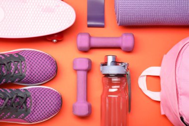 Turuncu arka planda farklı spor ekipmanları, düz yatış