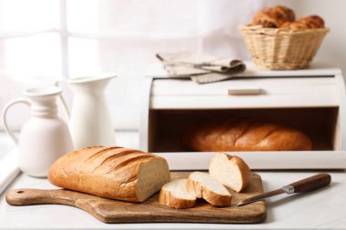 Mutfaktaki beyaz mermer masada yeni pişmiş somunlarla ahşap ekmek sepeti.