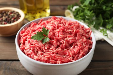 Tabakta çiğ et, maydanoz, baharat ve yağ, ahşap masa, yakın plan.