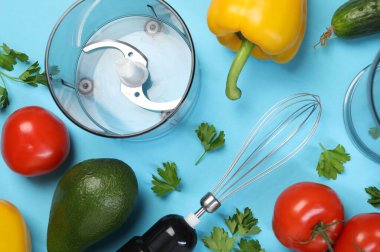 El blenderi seti ve açık mavi arka planda taze ürünler, düz konum