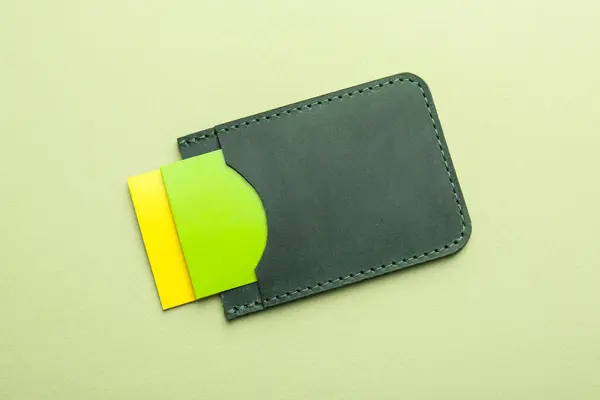 Stock image Leather business card holder with colorful cards on light green background, top view