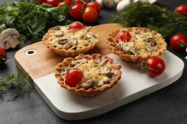 Peynirli, domatesli ve dereotlu turtalar karanlık masada, yakın plan.