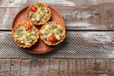Peynirli, domatesli, mantarlı ve ahşap kırsal masada dereotlu turtalar. Metin için boşluk
