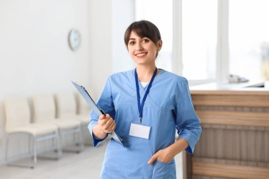 Portrait of smiling medical assistant with clipboard in hospital