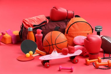 Kırmızı arka planda birçok farklı spor ekipmanı