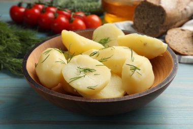 Açık mavi ahşap masada dereotlu haşlanmış patatesler, yakın plan.