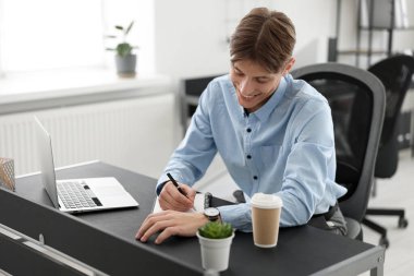 Ofisteki Webinar sırasında not alan adam.