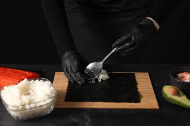 Eldivenli şef karanlık masada suşi yapıyor, yakın plan.