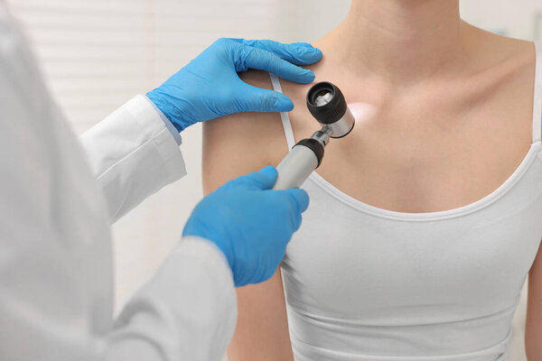 Dermatologist with dermatoscope examining patient in clinic, closeup