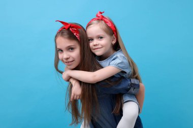 Açık mavi arka planda şirin küçük kız kardeşler