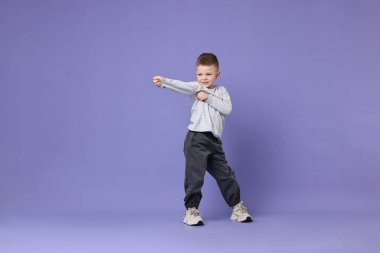 Mutlu küçük çocuk menekşe arka planda dans ediyor