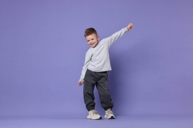 Mutlu küçük çocuk menekşe arka planda dans ediyor