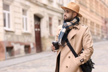 Açık havada kağıt bardaklı, sıcak eşarplı yakışıklı bir adam. Metin için boşluk