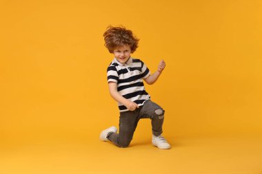 Sarı arka planda dans eden küçük mutlu çocuk