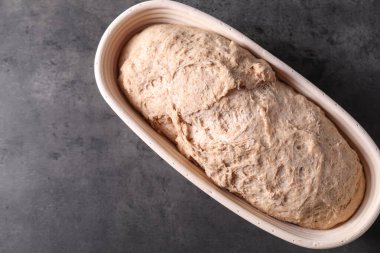 Gri masadaki düzeltme sepetinde taze ekmek hamuru, üst manzara. Metin için boşluk