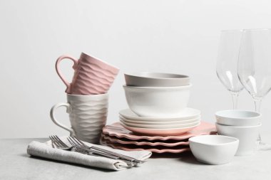 Seramik bulaşık takımı, bardaklar, bardaklar ve çatal bıçak takımı açık gri masada.