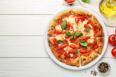 Lezzetli Margherita pizzası ve beyaz ahşap masa üzerindeki malzemeler, üst manzara. Metin için boşluk