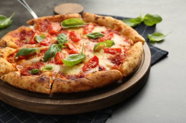 Lezzetli Margherita pizza ve fesleğen gri masada, yakın plan.