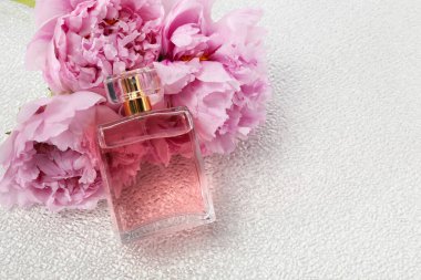 Beyaz plastik yüzeyde lüks parfüm ve çiçek dekoru, metin için boşluk