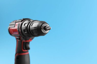 Açık mavi arka planda modern elektrikli tornavida, yakın plan. Metin için boşluk