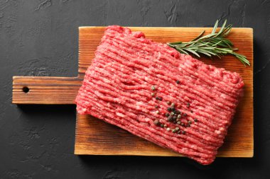 Çiğ et, biberiye ve biberiyeler siyah masanın üstünde.