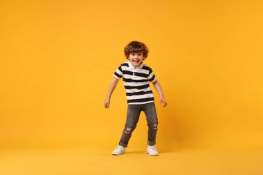Sarı arka planda dans eden küçük mutlu çocuk