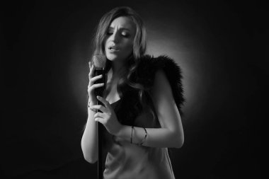 Mikrofonlu güzel bir şarkıcı, siyah beyaz efektli.