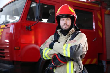 Firefighter in uniform near red fire truck at station