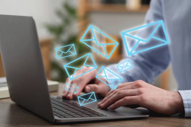 İçerideki masada dizüstü bilgisayarda yazan adam, yakın plan. Cihazdan gelen iletiler olarak birçok zarf çizimi