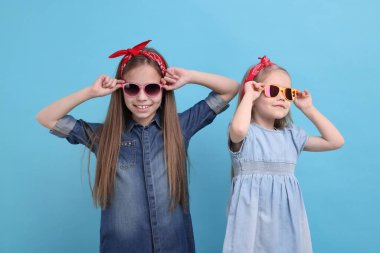 Açık mavi arka planda şirin küçük kız kardeşler