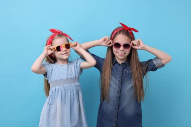 Açık mavi arka planda şirin küçük kız kardeşler