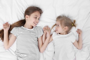 Yatakta sevimli küçük kız kardeşler, üst manzara.