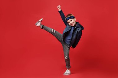 Kırmızı arka planda dans eden küçük mutlu çocuk